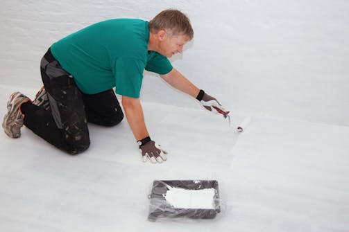 Male tregulv: Neste strøk maling rulles på. Male tregulv: Neste strøk maling rulles på.
